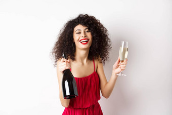 快乐聚会，派对女人红色的衣服笑持有瓶香槟玻璃喝有趣的庆祝假期站白色背景