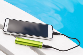 智能手机连接绿色可移植的电池充电器Usb电缆蓝色的<strong>水</strong>背景紧急充电电话<strong>懒</strong>人游泳池休息
