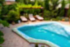 摘要模糊背景蓝色的游泳池日光浴浴床酒店度假胜地假期假期休闲背景概念