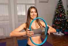 年轻的女人魔法普拉提环健身教练运动服装紧身裤上衣伸展运动健身房瑜伽席大窗口阳光明媚的一天女健身瑜伽例程概念