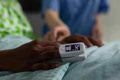 特写镜头非洲美国生病的病人休息床上医疗血氧计手指