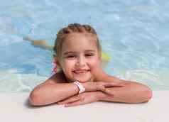 微笑女孩游泳在游泳池边