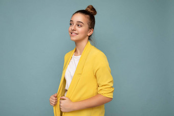 侧面轮廓拍摄有吸引力的积极的快乐微笑浅黑肤色的女人女孩穿休闲黄色的夹克白色t恤站孤立的蓝色的背景墙一边
