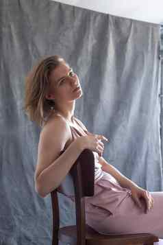 高加索人年轻的女人短头发粉红色的西装坐着椅子工作室