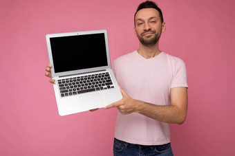 英俊的微笑褐色男人。持有移动PC电脑相机t恤孤立的粉红色的背景