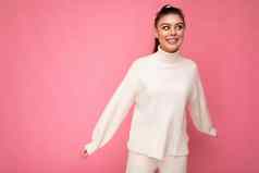 年轻的美丽的快乐积极的微笑时尚的浅黑肤色的女人女人穿休闲白色毛衣平衡孤立的粉红色的背景墙有趣的快乐概念复制空间