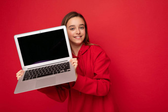 特写镜头肖像<strong>照片</strong>美丽的快乐微笑女孩长头发穿红色的连帽衫持有电脑移动PC相机孤立的红色的<strong>墙背景</strong>