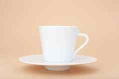 关闭白色陶瓷咖啡杯飞碟柔和的米色背景复制空间