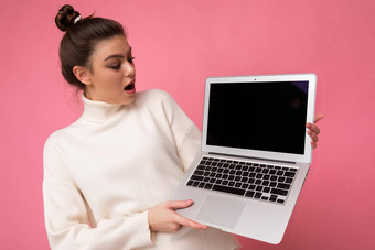 <strong>照片</strong>美丽的惊讶惊讶女人<strong>聚集</strong>浅黑肤色的女人头发穿白色毛衣持有电脑移动PC开放上网本孤立的粉红色的墙背景