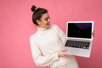 <strong>照片</strong>美丽的女孩聚集浅黑肤色的女人头发穿白色毛衣持有电脑移动PC上网本孤立的粉红色的<strong>墙背景</strong>