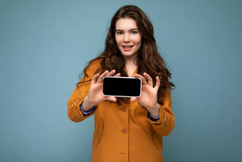 照片美丽的微笑年轻的女人好穿休闲时尚的装站孤立的背景复制空间持有智能手机显示电话手空屏幕显示模型相机
