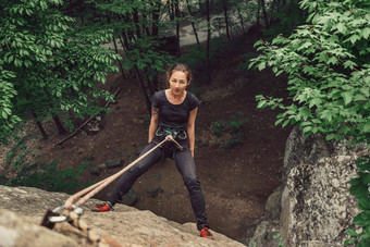 登山者年轻的女人站石头岩石