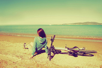 女孩坐着自行车海滩
