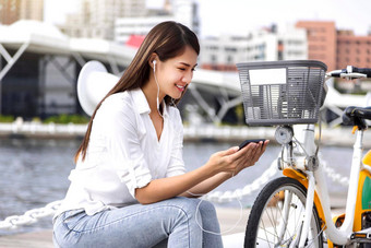 年轻的女人移动电话自行车分享服务