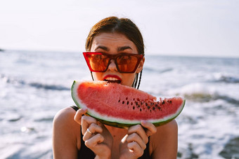 快乐的女人太阳镜吃西瓜海洋