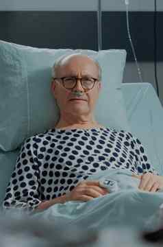 肖像老病人坐着医院病房床上