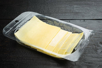 瑞士奶酪片塑料包黑色的木表格背景