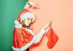 年轻的女人可爱的女孩漂亮的脸圣诞节圣诞老人持有圣诞节长袜橙色绿色isoalted背景