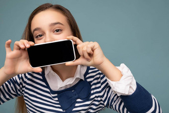 特写镜头照片漂亮的积极的浅黑肤色的女人女孩穿条纹长袖站孤立的蓝色的背景复制空间持有智能手机显示电话手空屏幕显示模型指出gadjet相机