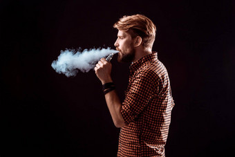 年轻的男人。吸烟电子香烟