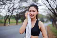 年轻的运动女人休息擦拭汗水毛巾锻炼体育运动练习在户外公园