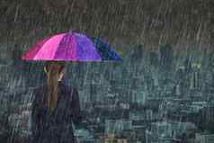 业务女人持有五彩缤纷的伞下降雨城市背景