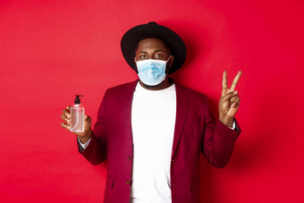 科维德检疫假期概念年轻的非洲美国男人。医疗面具显示手洗手液和平标志推荐防腐剂