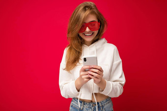 照片拍摄有吸引力的积极的好年轻的女人穿休闲时尚的装平衡孤立的背景空空间持有手移动电话消息传递短信智能手机显示屏幕