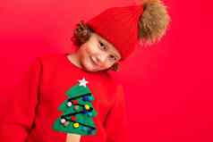 很酷的男孩卷发红色的背景毛衣圣诞节树