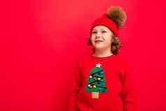 快乐的有趣的男孩红色的背景温暖的他毛衣圣诞节树