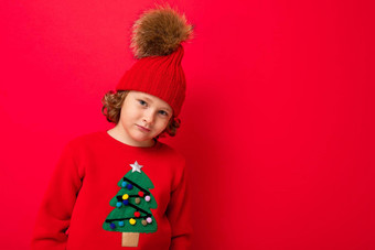 很酷的金发碧眼的孩子温暖的他毛衣圣诞节树红色的背景愚弄圣诞节概念