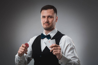 年轻的男人。衬衫马甲显示卡片持有扑克芯片手工作室拍摄