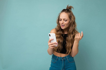 照片拍摄有吸引力的积极的好年轻的女人穿休闲时尚的装平衡孤立的背景空空间持有手移动电话消息传递短信智能手机显示屏幕