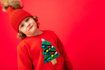 很酷的金发碧眼的孩子温暖的他毛衣圣诞节树红色的背景愚弄圣诞节概念