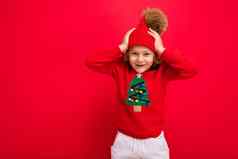 快乐的有趣的男孩红色的背景温暖的他毛衣圣诞节树