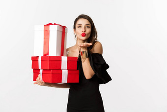 庆祝活动圣诞节假期概念漂亮的女人优雅的黑色的衣服持有礼物发送空气吻相机站白色背景