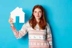 真正的房地产概念图像可爱的红色头发的人女孩好奇的纸房子模型思考购买财产复制空间蓝色的背景