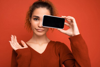 特写镜头照片年轻的女人穿黑暗红色的毛衣孤立的红色的背景持有智能手机显示移动电话屏幕复制空间断路相机