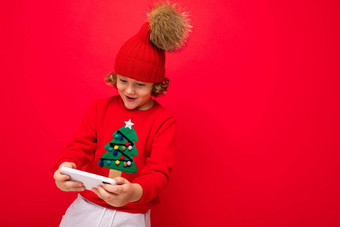 年轻的男人。智能<strong>手机</strong>手背景红色的墙针织他毛衣圣诞<strong>节</strong>树