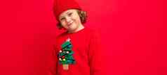 很酷的男孩卷发红色的背景毛衣圣诞节树