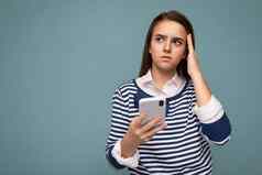 照片深思熟虑的集中有吸引力的年轻的浅黑肤色的女人女孩穿条纹朗斯利耶夫站孤立的蓝色的背景冲浪互联网电话思考