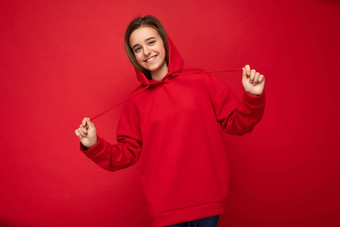 照片拍摄美丽的快乐微笑浅黑肤色的女人女孩穿时尚的红色的连帽衫站孤立的红色的背景墙相机