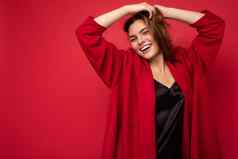 年轻的美丽的欧洲时尚的浅黑肤色的女人女人穿黑色的上衣前红色的开襟羊毛衫孤立的红色的背景积极的真诚的情绪简单的自然相机免费的空间