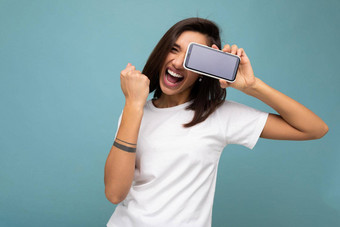 有吸引力的微笑年轻的褐色女人好穿白色t恤站孤立的蓝色的背景复制空间持有智能手机显示电话手空屏幕屏幕断路显示手势