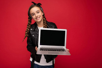 照片美丽的快乐微笑女孩褐色辫子持有电脑移动PC穿黑色的夹克大手帕孤立的红色的墙背景相机