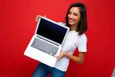 美丽的快乐喜出望外年轻的女人短黑暗浅黑肤色的女人发型持有电脑移动PC相机穿白色t恤牛仔裤孤立的红色的墙背景