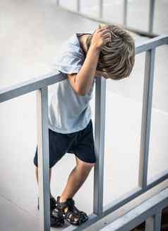 垂直孩子男孩站桥边缘栅栏触摸头头发孩子心理问题孤独恐惧不满自杀尝试风险保护因素警告迹象