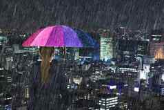 业务女人持有五彩缤纷的伞下降雨城市背景