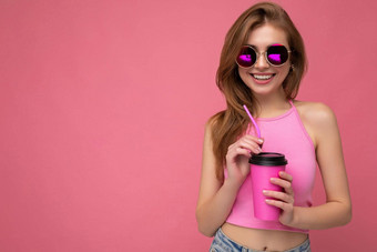 照片有吸引力的年轻的快乐微笑金发女郎女人穿日常时尚的衣服孤立的色彩鲜艳的背景墙持有纸杯断路喝茶相机