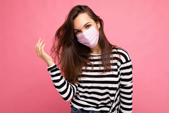 年轻的漂亮的女人可重用的病毒保护粉红色的面具脸冠状病毒孤立的粉红色的背景墙